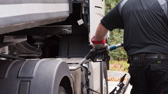 Zu sehen ist ein Mann, welcher einen Lkw betankt.