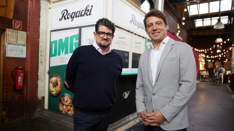 Jan Spielhagen und Daniel-Jan Girl stehen vor dem Pop-up-Wagen des Rogacki in der Markthalle Neun.