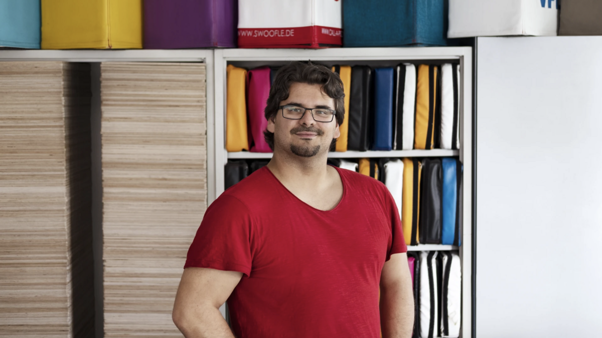 Ein Mann positioniert vor einem Regal. Es ist Georg Winkel, Gründer der Möbelmanufaktur Swoofle
