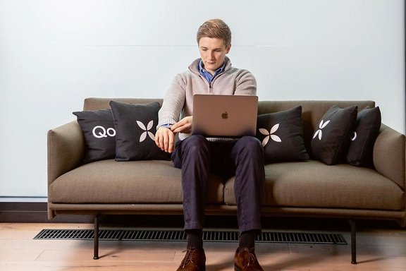Junger Mann sitzt mit Laptop auf einem Sofa