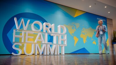 Zu sehen ist ein Flur in dem eine Logoaufsteller des World Health Summit in Berlin 2025 steht.
