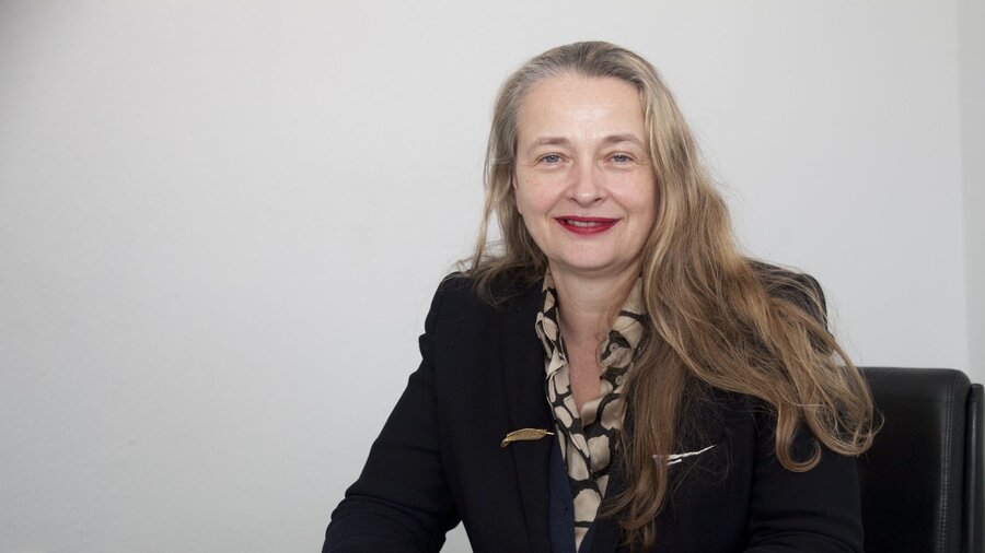 Zu sehen ist eine Frau mit langen Haaren im Portraitfoto, sie lächelt in die Kamera.
