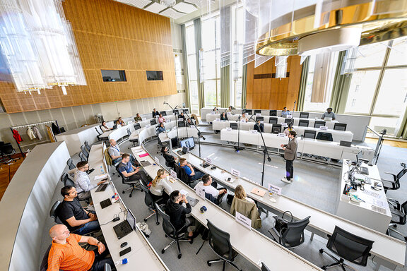 Ein heller Hörsaal mit Studierenden und einem Dozenten