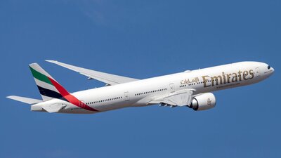 Zu sehen ist ein weißes Passagierflugzeug in blauem Himmel. Es ist eine Maschine der Fluggesellschaft Emirates.