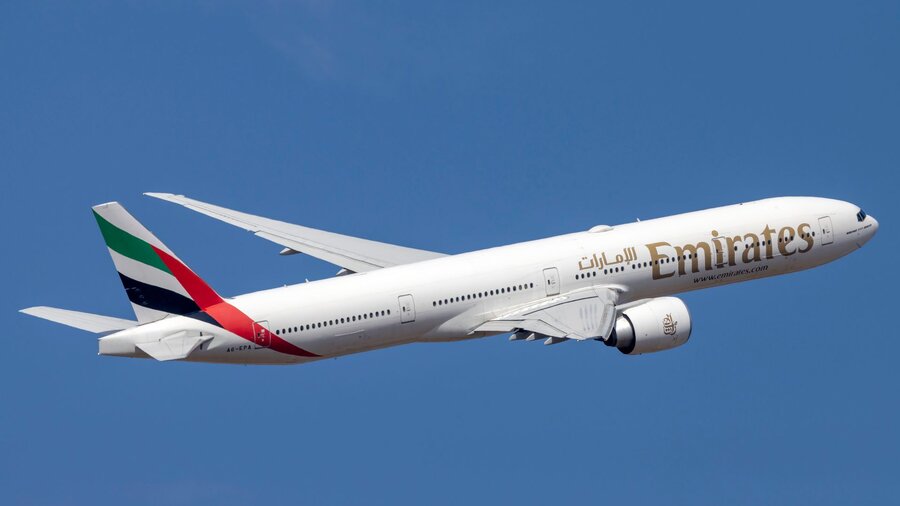 Zu sehen ist ein weißes Passagierflugzeug in blauem Himmel. Es ist eine Maschine der Fluggesellschaft Emirates.