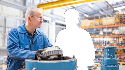Foto von zwei Personen in einer Werkstatt. Eine der beiden Personen ist aus dem Bild geschnitten.