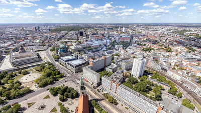 Luftaufnahme von Berlin mit der St.-Matthäus-Kirche im Vordergrund und dem Potsdamer Platz im Hintergrund bei klarem Himmel