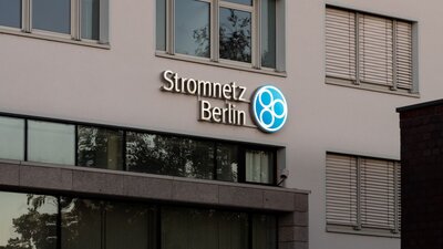 Zu sehen ist eine Hausfassade mit mehreren Fenstern. Daran angebracht ist das Logo von Stromnetz Berlin.