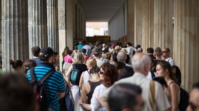 Zu sehen ist eine Fußgängerpassage in der Friedrichstraße in Berlin, auf der zahlreiche Menschen unterwegs sind.