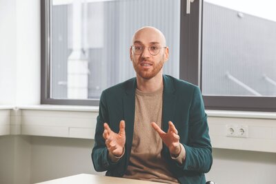 Zu sehen ist ein mittelalter Mann mit Glatze in einem wildgrünen Sakko. Es handelt sich um Fabian Ahlberg, Geschäftsführer der Ahlberg Metalltechnik GmbH.