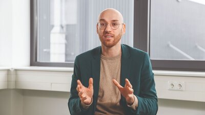 Zu sehen ist ein mittelalter Mann mit Glatze in einem wildgrünen Sakko. Es handelt sich um Fabian Ahlberg, Geschäftsführer der Ahlberg Metalltechnik GmbH.