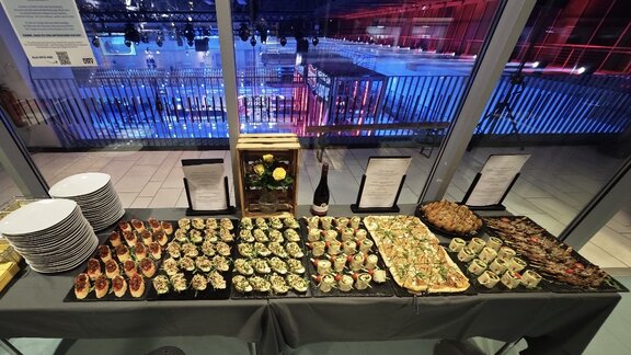 Fingerfood-Buffet steht vor einer Glasscheibe mit Blick in ein TV-Studio