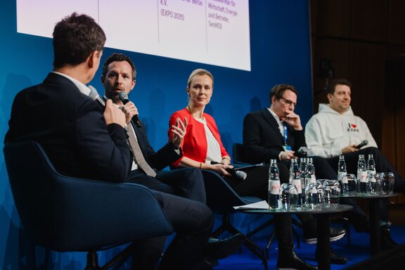 Vier Personen sitzen auf einer Bühne und unterhalten sich vor Publikum.