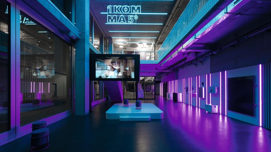 Zu sehen ist ein neon-lila-beleuchtetes Bürogebäude. Es handelt sich um das TechLab Berlin der Firma 1Komma5°.