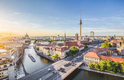 Zu sehen ist eine Großstadt von oben, durch die ein Fluss fließt. Es handelt sich um Berlin und die Spree.