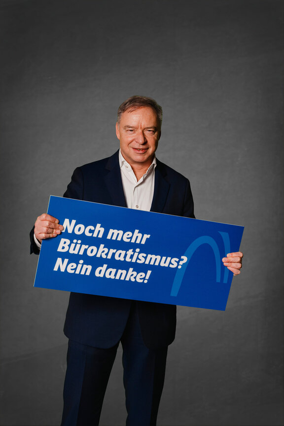 Eine Person steht vor einem neutralen grauen Hintergrund und hält ein großes blaues Schild mit der weißen Aufschrift: "Ja zur Ausbildung. Nein zur Abgabe!"
