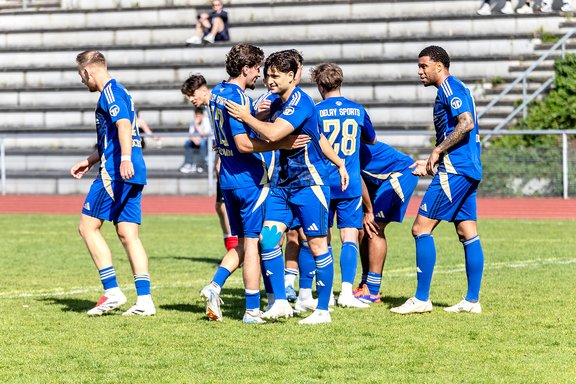 Fußballspieler in blauen Trikots feiern auf dem Spielfeld während eines Spiels im Stadion