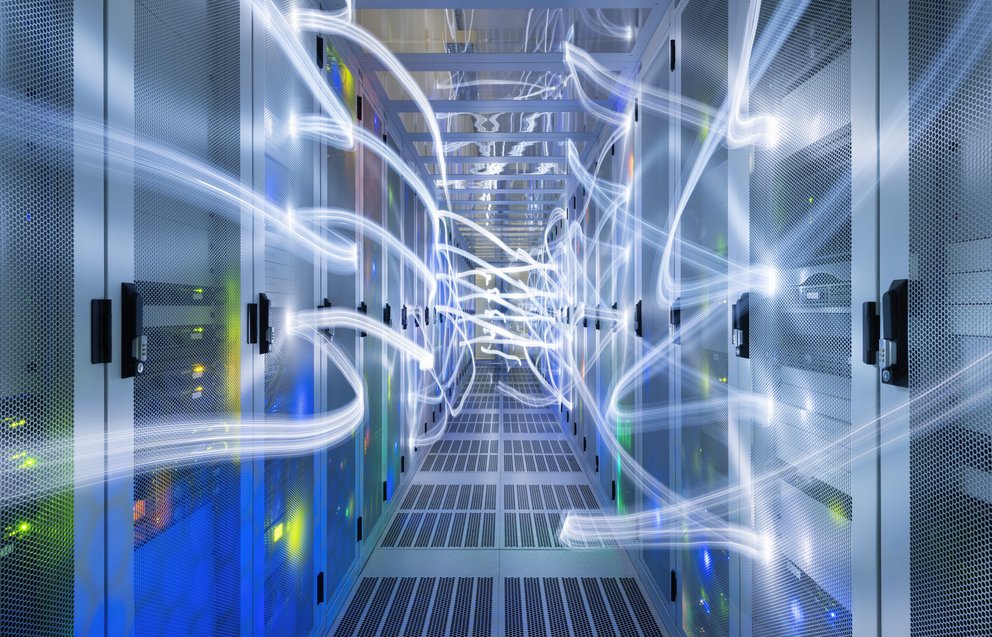 Reihen von Serverracks in einem Rechenzentrum mit Lichtspuren, die Datenfluss symbolisieren
