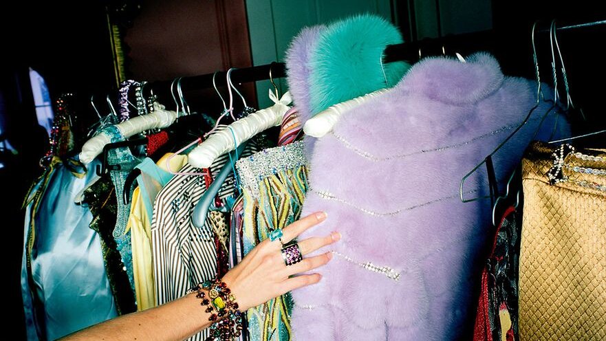 Eine Hand, welche nach einem Kleidungsstück auf einer Kleiderstange greift