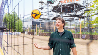 Ein Mann mittleren Alters steht am Netz eines Beachvolleyballfeldes.
