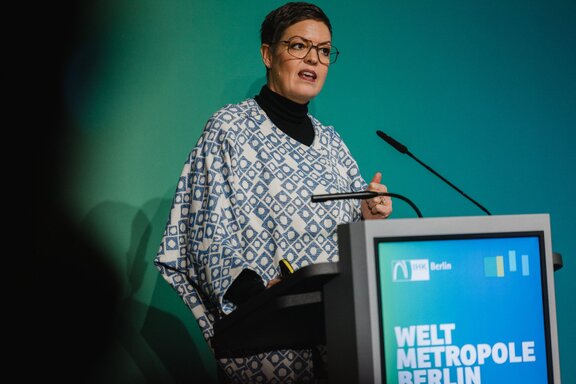 Eine Frau spricht auf einer Bühne am Redepult.