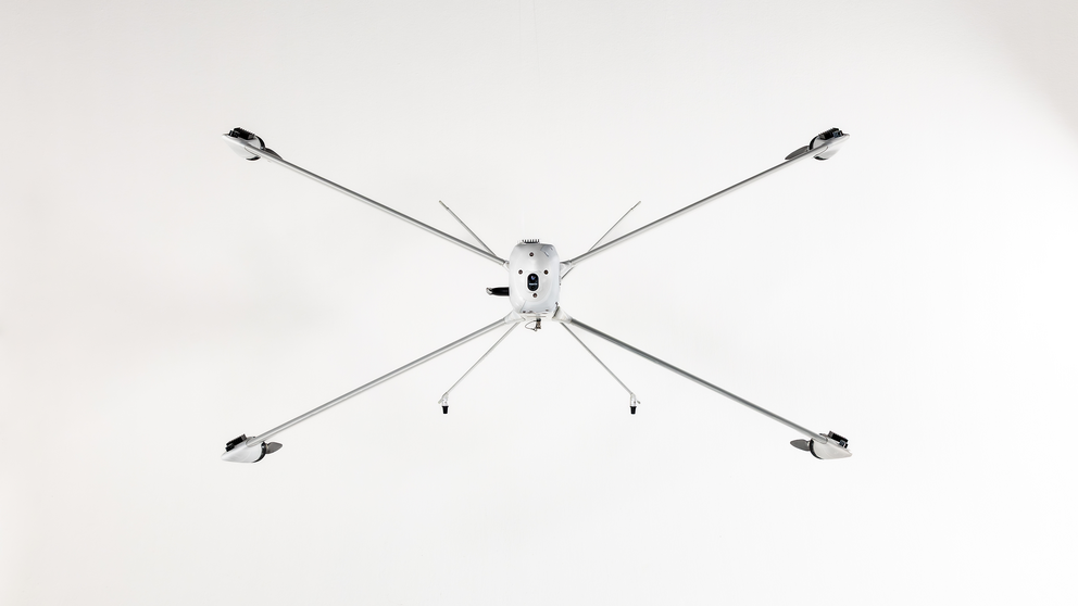 Drohne mit sechs langen, dünnen Armen und Propellern, frontal von unten fotografiert.