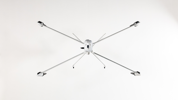 Drohne mit sechs langen, dünnen Armen und Propellern, frontal von unten fotografiert.