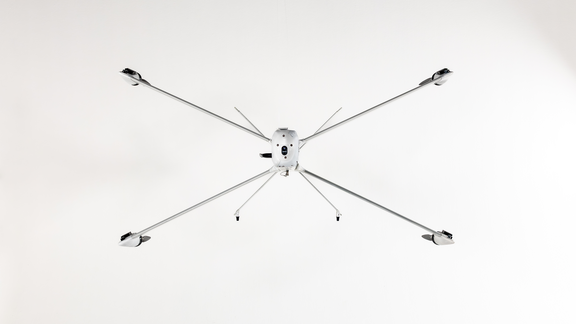 Drohne mit sechs langen, dünnen Armen und Propellern, frontal von unten fotografiert.