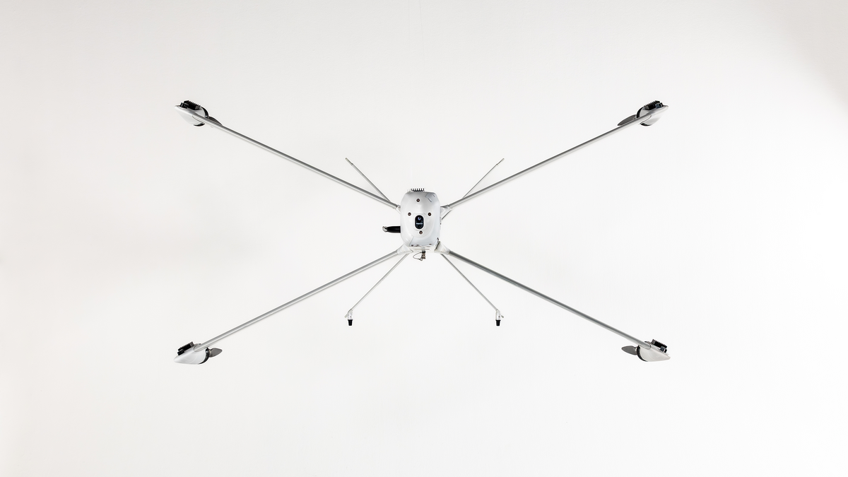 Drohne mit sechs langen, dünnen Armen und Propellern, frontal von unten fotografiert.