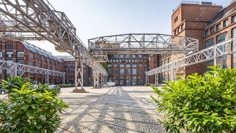 Zu sehen ist eine Gewerbehof, dessen Häuser aus rotem Backstein bestehen. Es handelt sich um den Gewerbehof Amperium am Humboldthain in Berlin mitte.