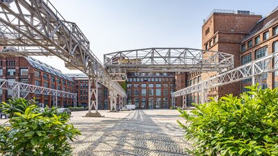 Zu sehen ist eine Gewerbehof, dessen Häuser aus rotem Backstein bestehen. Es handelt sich um den Gewerbehof Amperium am Humboldthain in Berlin mitte.