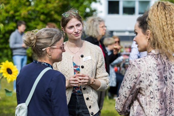 zu sehen sind vier Frauen, die sich stehend unterhalten.