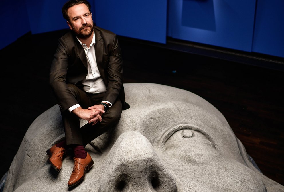 Ein Mann sitzt auf dem Kopf eines Museumsexponats.