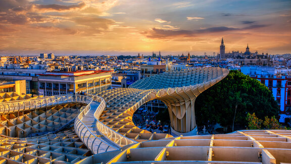 Im Vordergrund steht der Metropol Parasol, eine Holzkonstruktion in Pilzform. Dahinter ist die Skyline von Sevilla.  