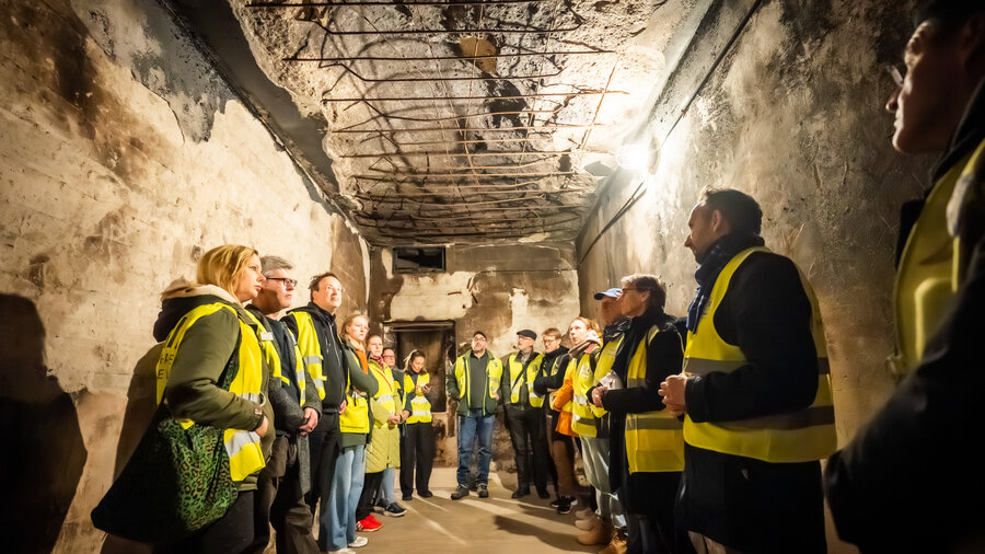 Eine Gruppe von Menschen steht in Warnwesten in einem unterirdischem Tunnel