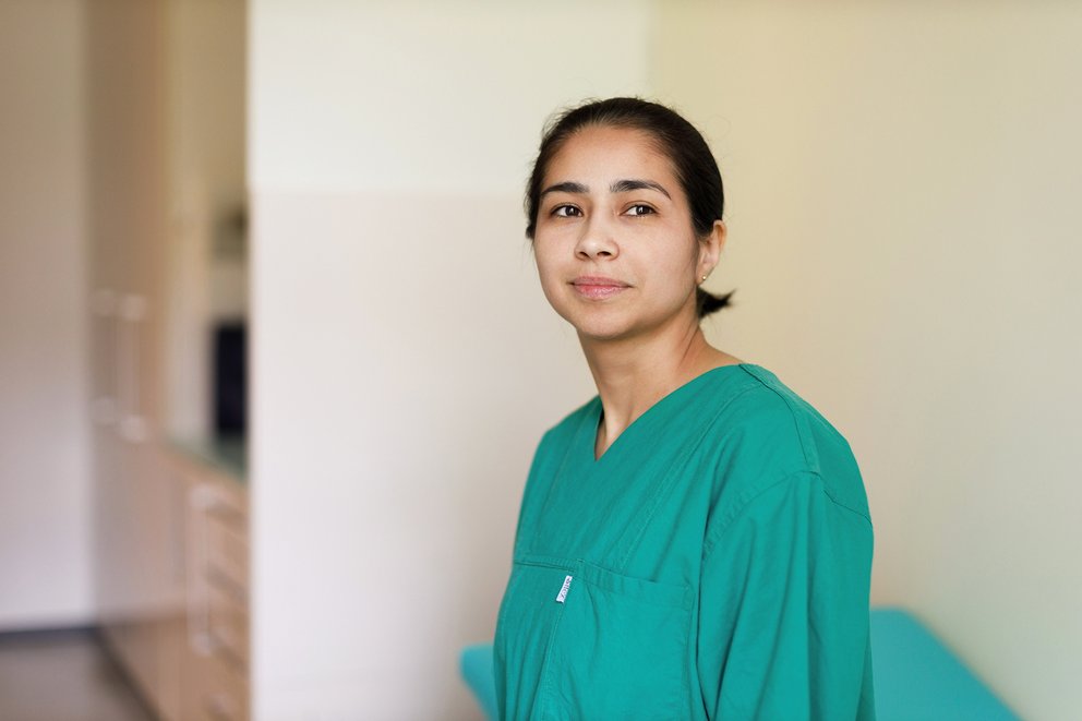 Suryann Santos Junge Frau in grüner medizinischer Arbeitskleidung blickt nach rechts, neutraler Hintergrund