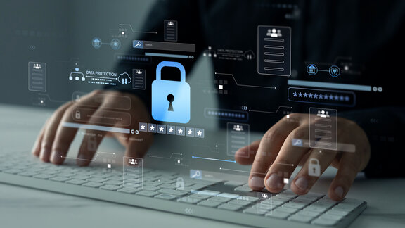 Zwei Hände tippen auf einem Keyboard. Darüber sind Symbole aus der Cybersicherheit abgebildet