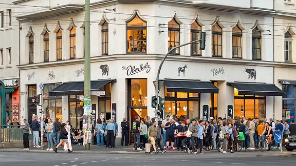 Menschenmenge vor dem Café 'St. Oberholz' an einer Straßenecke in Berlin bei Dämmerung