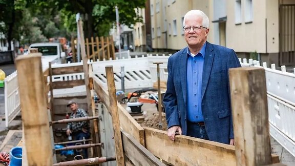 Ein weißhaariger Mann steht an einer Baustelle.