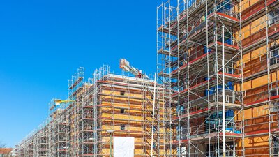 Zu sehen sind zwei Mehrfamilienhäuser mit Baugerüst. Man sieht eine Wohnungsbaustelle.