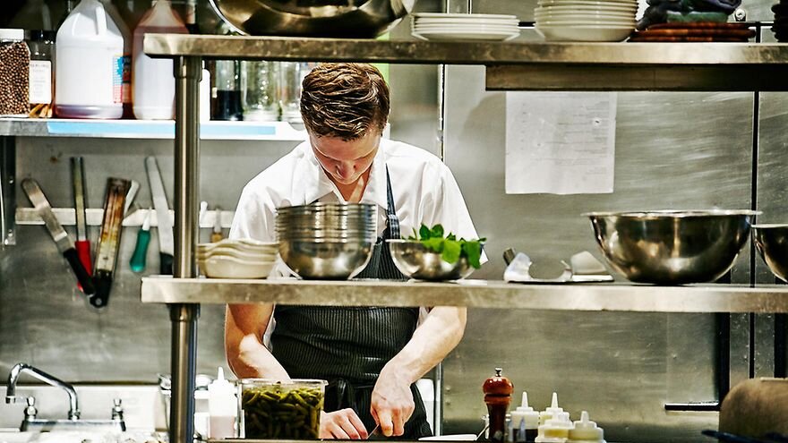 Foto eines Kochs, welcher in der Küche arbeitet.