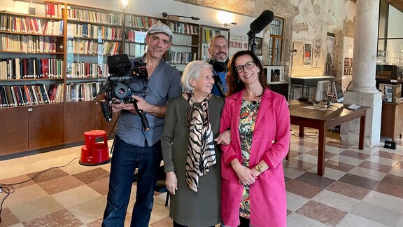 Ein Gruppe aus vier Menschen mit Filmequipment steht in einer alten Buchhandlung.