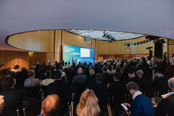Blick auf das Publikum und die Bühne in einem Vortragssaal.