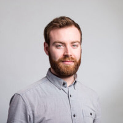 Ein junger Mann im Porträt vor einem grauen Hintergrund. Es ist Fried Große-Dunker, Co-Founder von The Dark Horse 