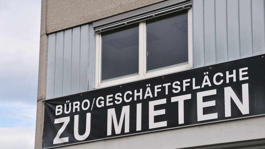 Zu sehen ist die Fassade und eine Fenster eines Bürohauses. Unter dem Fenster hängt ein Schild mit der Aufschrift: "BÜRO/GESCHÄFTSFLÄCHE ZU MIETEN".