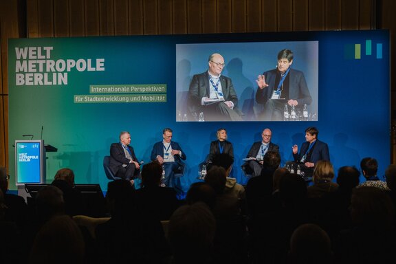 Fünf Personen sitzen auf einer Bühne vor Publikum und unterhalten sich.