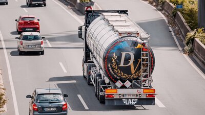 Zu sehen ist eine Autobahn, auf der mehrere Autos und ein LKW fahren.