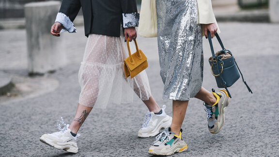 Beine von zwei modisch bekleidete Menschen, die auf der Straße laufen.