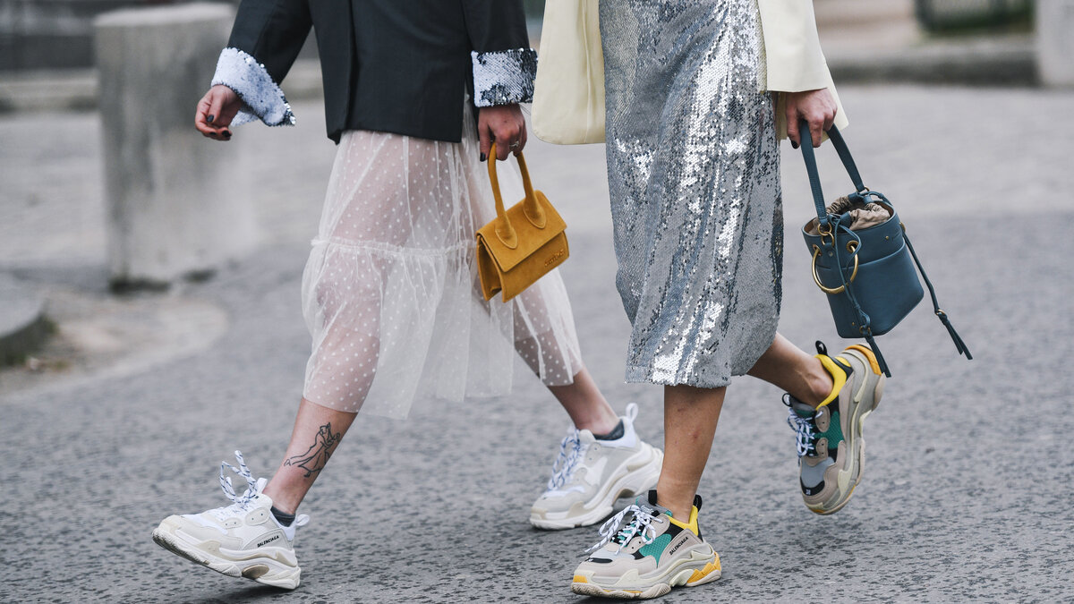 Beine von zwei modisch bekleidete Menschen, die auf der Straße laufen.