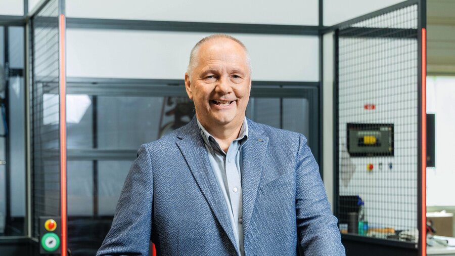 Zu sehen ist ein älterer Herr mit kurzen weißen Haaren und blauem Sakko, der freundlich in die Kamera schaut.